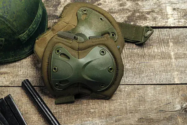Military knee pads on wooden surface